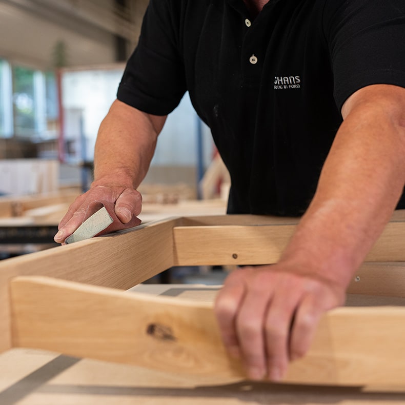 Ein Mitarbeiter von Junghans schleift an einem Holz-Werkstück in der Werkstatt, um mit seiner Erfahrung einen Prototyp zu entwickeln ab Auflage 1.